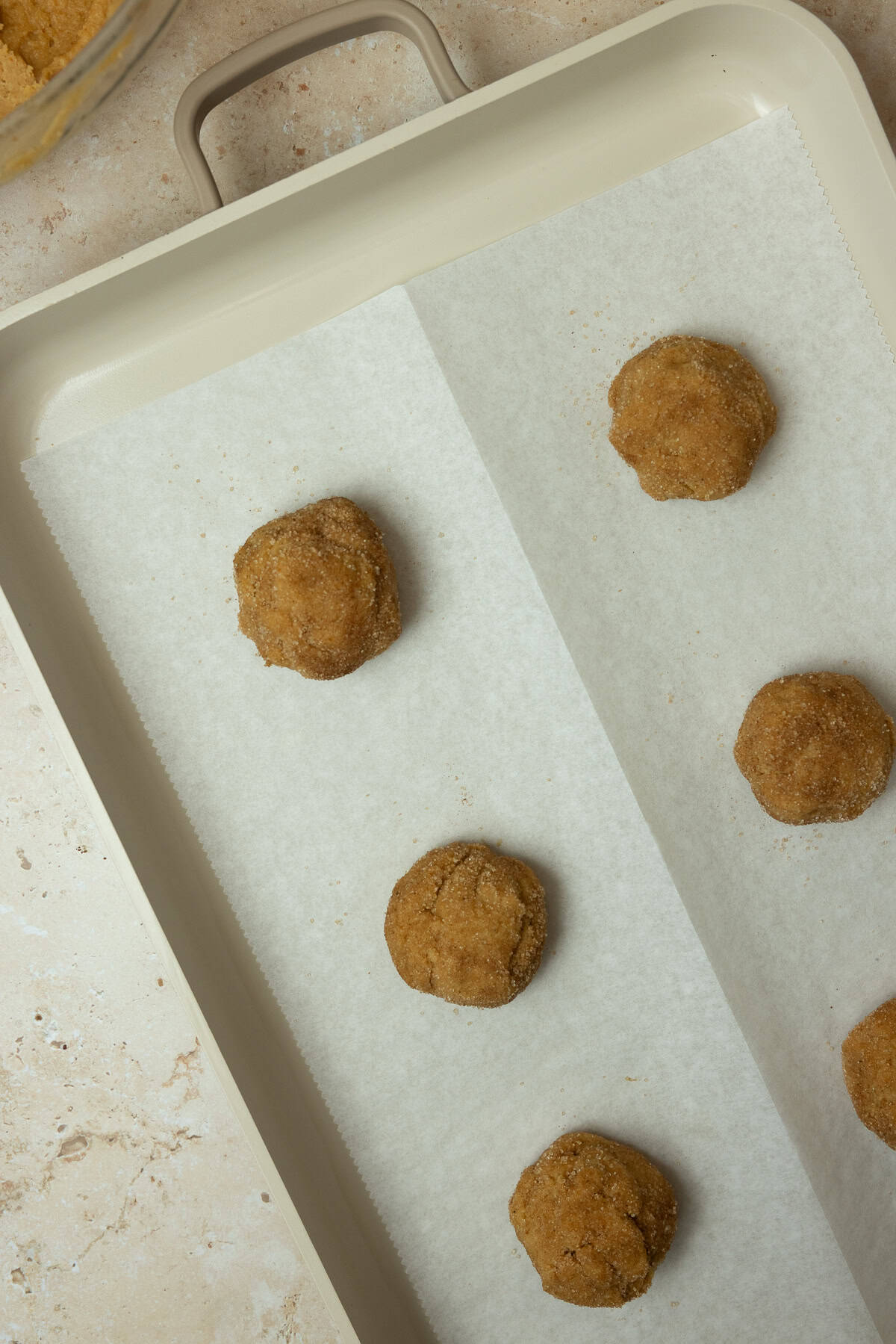 Cookie balls on a parchment lined baking sheet.