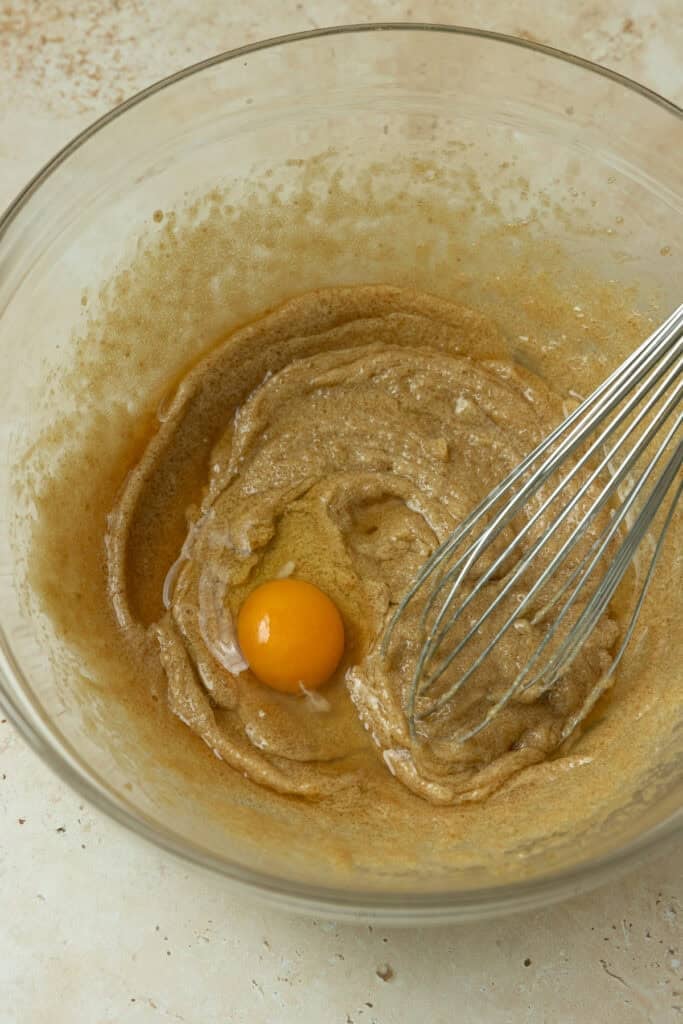 Egg yolk added to a mixing bowl with wet ingredients.