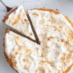 one slice of pumpkin cheesecake being pulled away from the entire cheesecake.