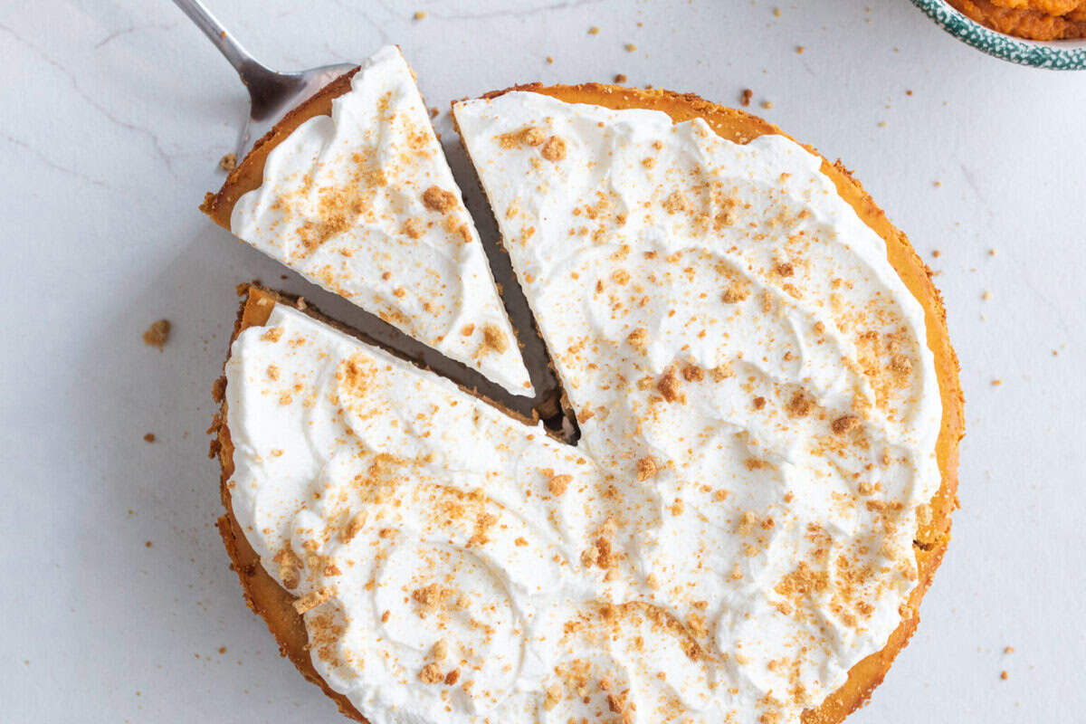 one slice of pumpkin cheesecake being pulled away from the entire cheesecake.