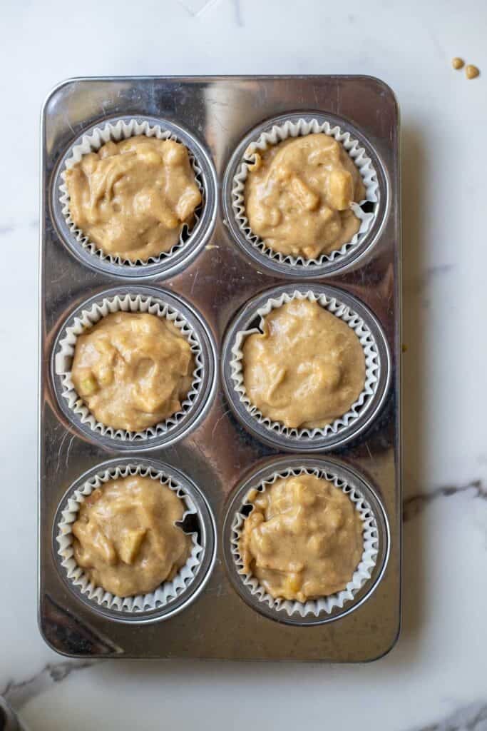 Muffin batter in a lined muffin tin ready to bake.