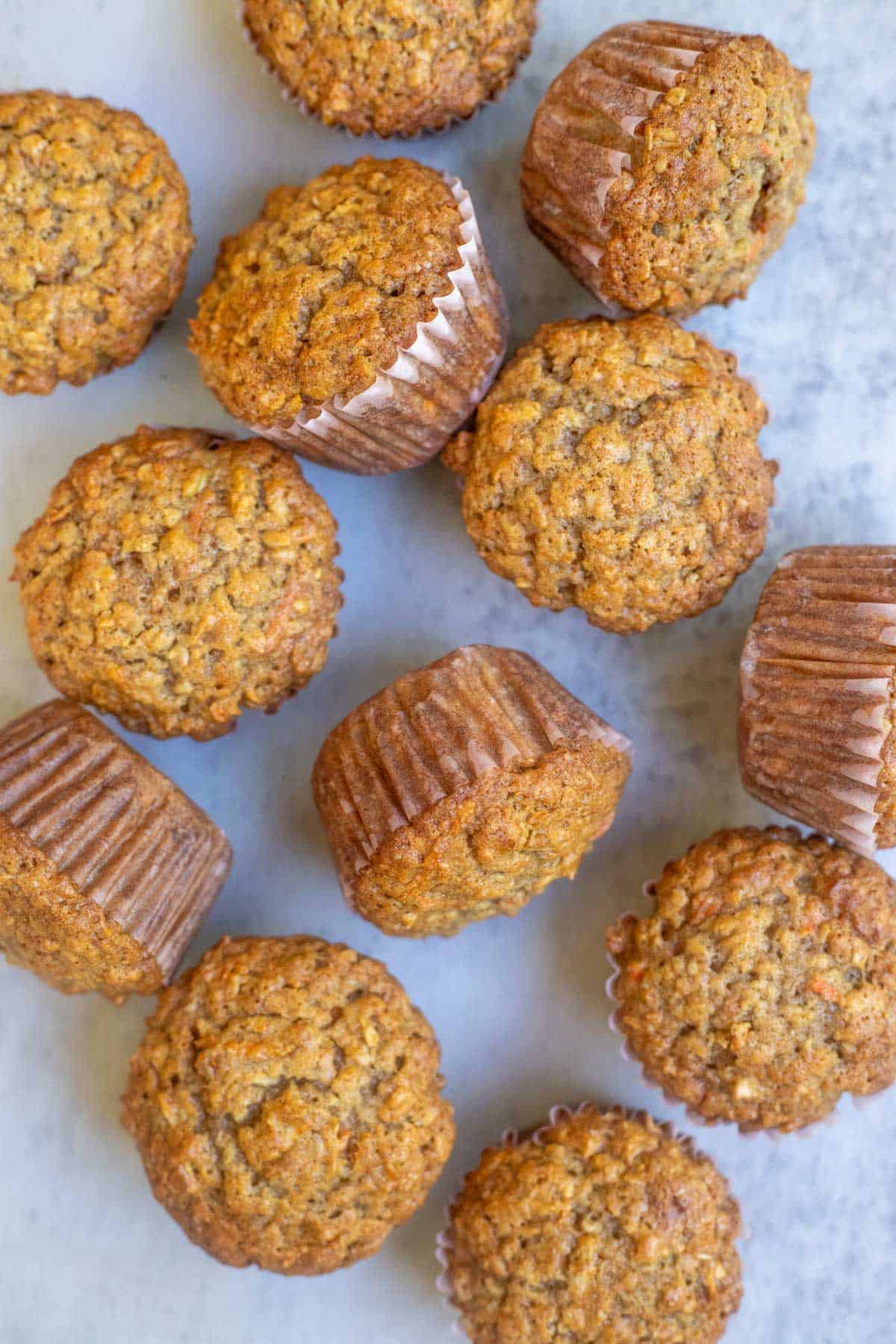 12 apple and carrot muffins laying on the marble counter top.