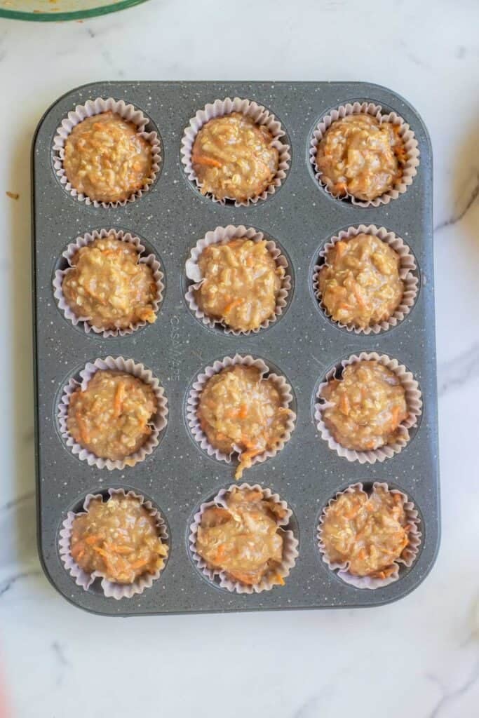 Muffin batter poured in a muffin tin with 12 muffins.