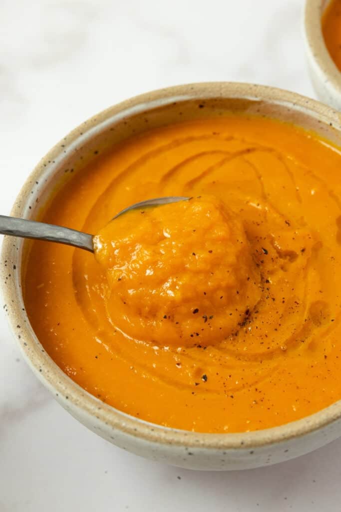 Black pepper topping the soup with a spoon taking soup out.