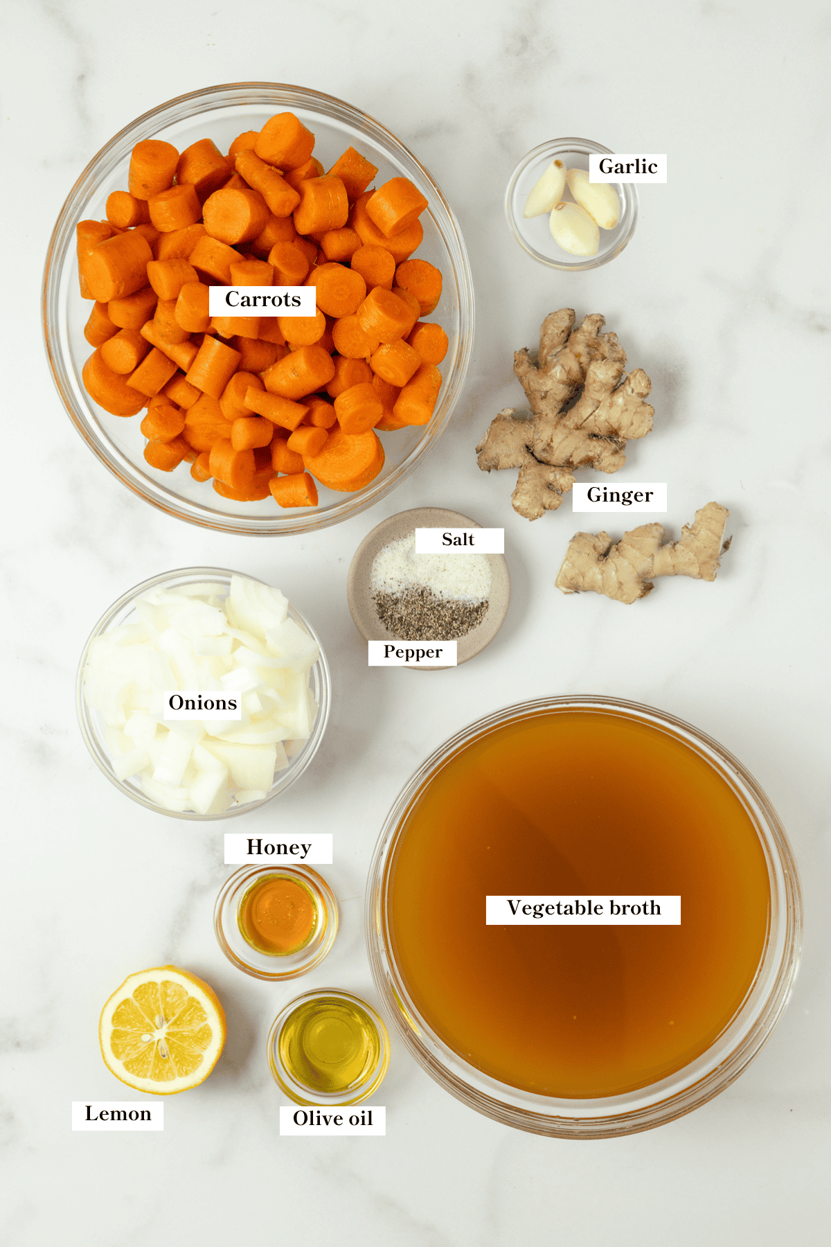 Carrot, ginger, broth, honey, salt, pepper, and more ingredients on the counter.