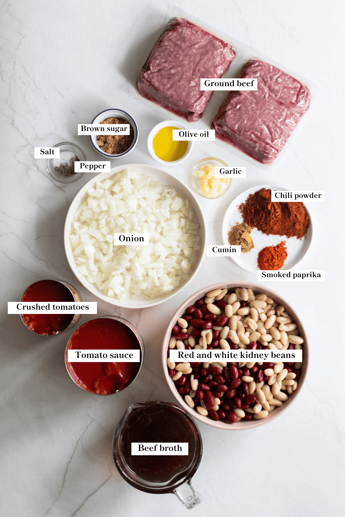 Ground beef, beans, spices, and other ingredients spread out on a countertop.
