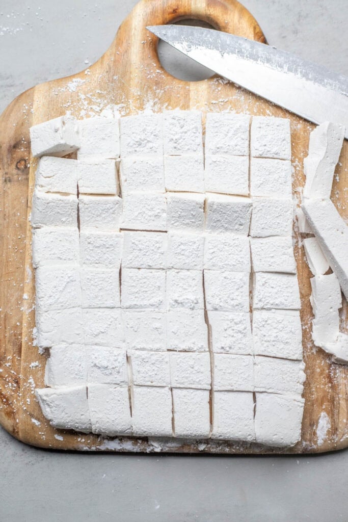 Marshmallows on a cutting board cut into squares.