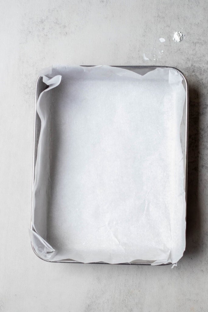 A 9x9 pan lined with parchment paper.