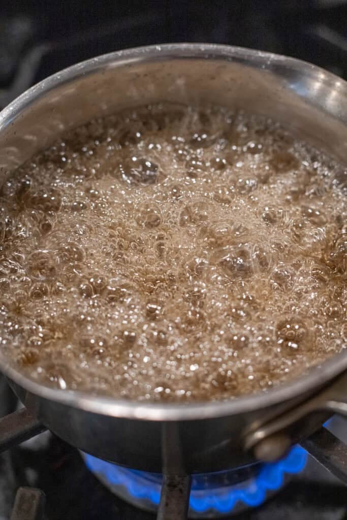 A boiling pot of sugar syrup in a pot on the stove.