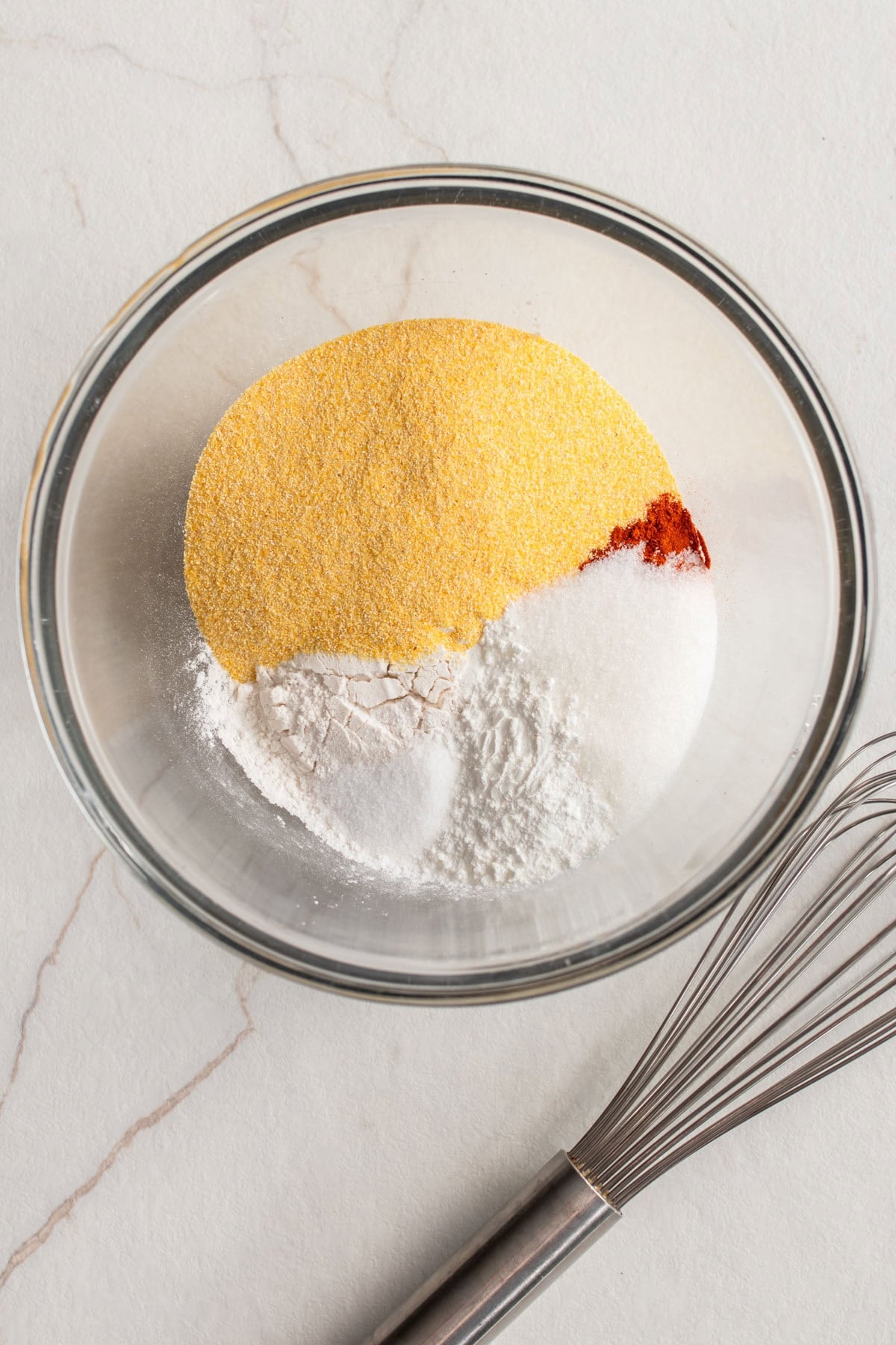 Flour, paprika, corn meal, and other ingredients in a glass bowl.
