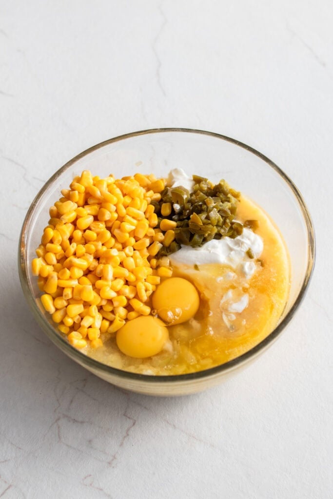 Large bowl filed with eggs, corn, jalapeño, sour cream and other ingredients. 