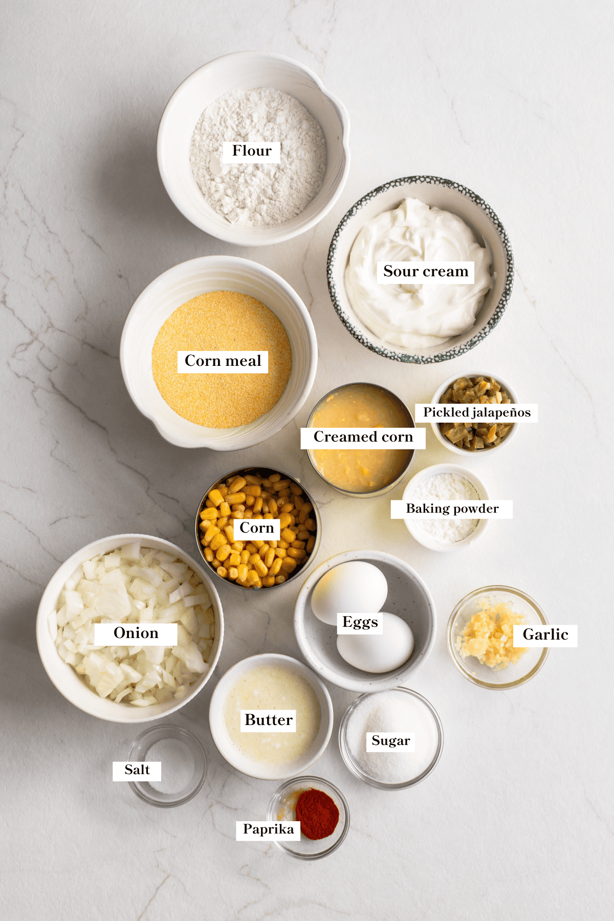 Small bowls of corn casserole ingredients like corn, corn meal. eggs, and more.