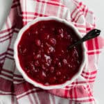 a bowl of cranberry sauce on a red plaid tea towel.