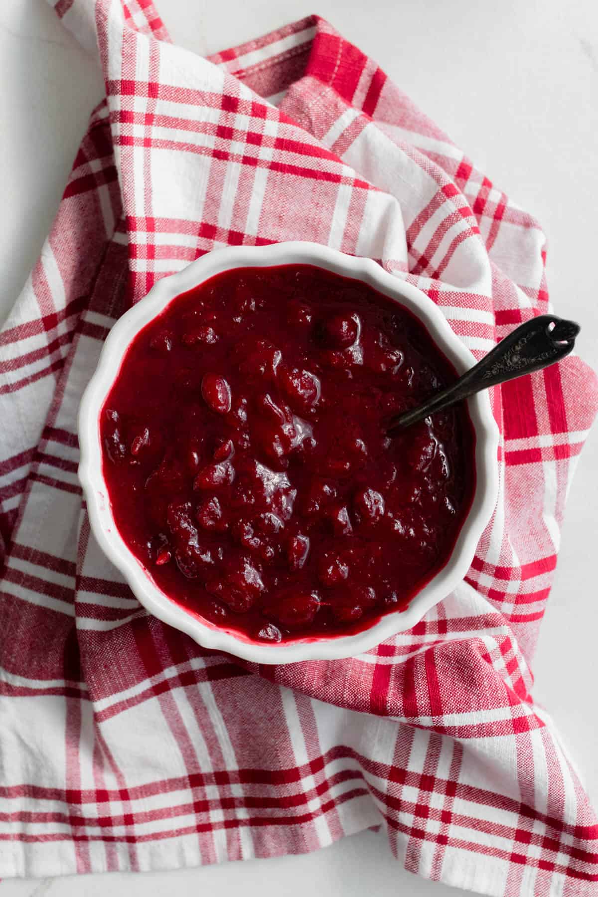 a bowl of cranberry sauce on a red plaid tea towel.