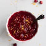 a bowl of cranberry sauce on the counter with a serving spoon in the side of the bowl.