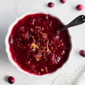 a bowl of cranberry sauce on the counter with a serving spoon in the side of the bowl.