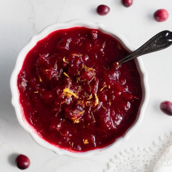 a bowl of cranberry sauce on the counter with a serving spoon in the side of the bowl.