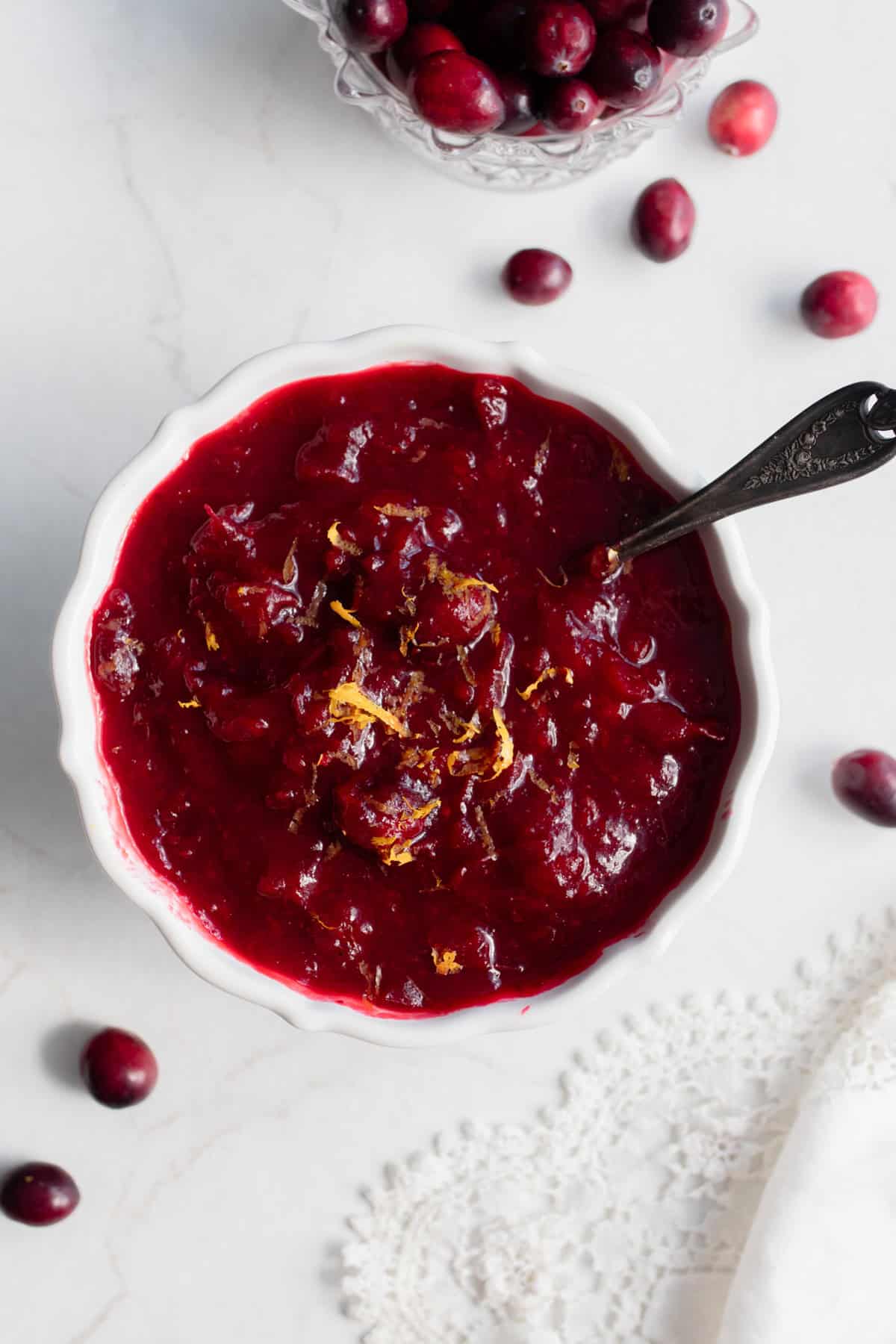 a bowl of cranberry sauce on the counter with a serving spoon in the side of the bowl.