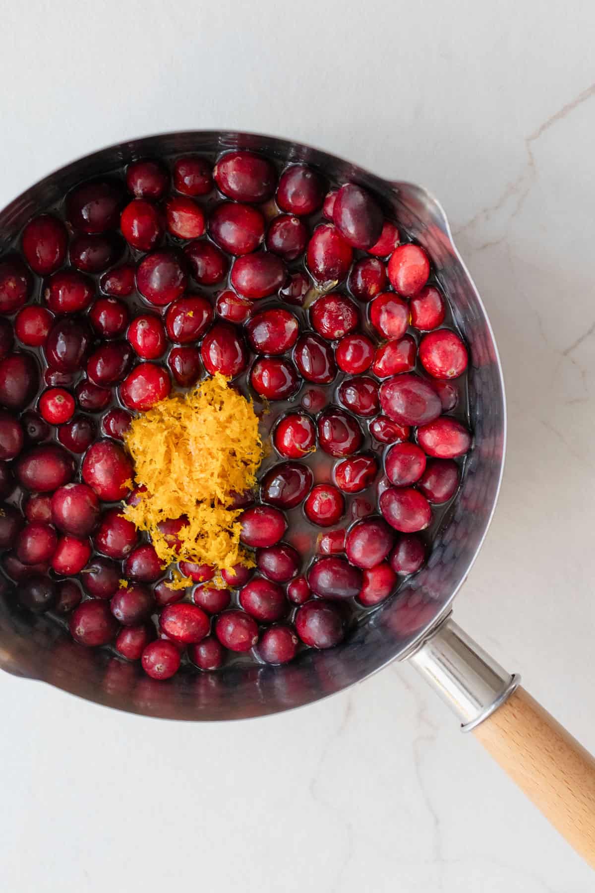 Cranberries and orange zest in a large pot over the stove.