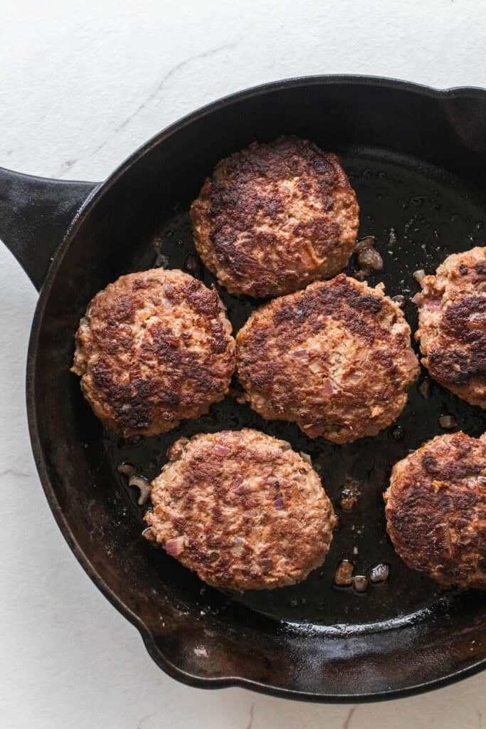 Cooking Salisbury steak patties in a cast iron skillet.