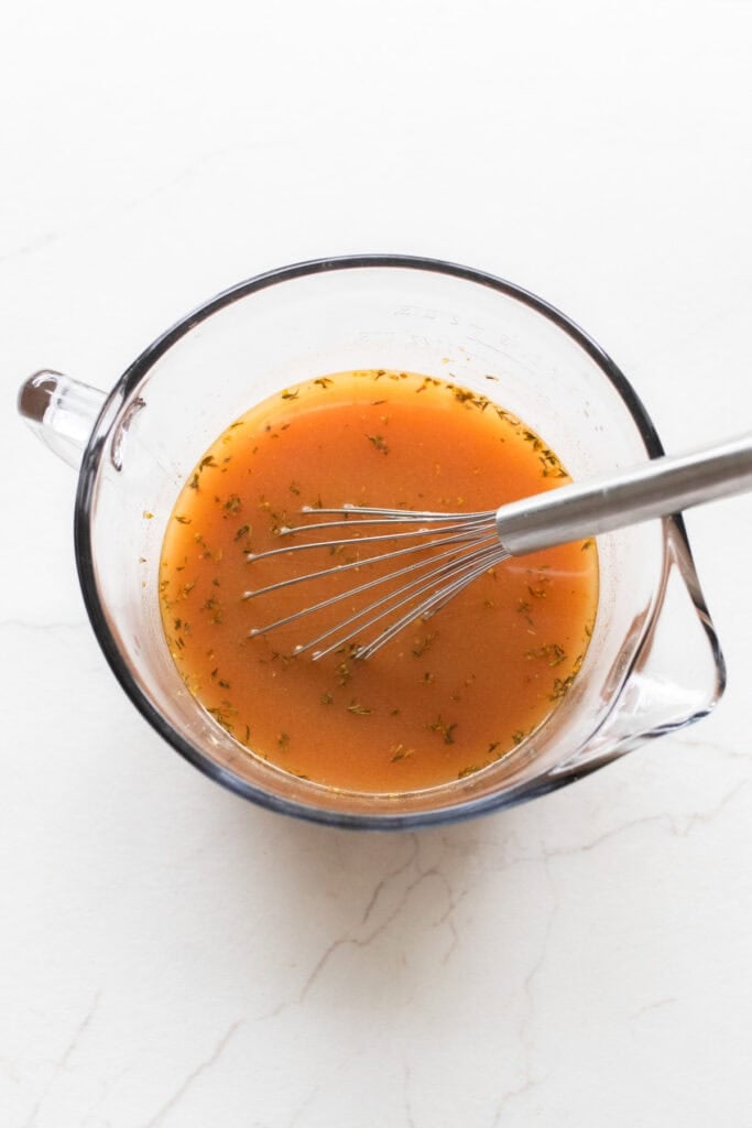 Whisking beef broth, spices, and tomato paste in a bowl.