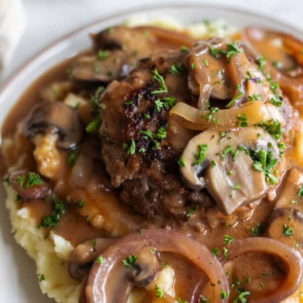 Salisbury steak with mushrooms, onions, on mashed potatoes and covered in gravy and parsley.