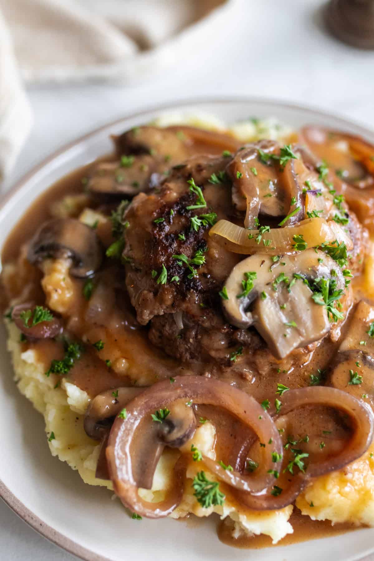 Salisbury steak with mushrooms, onions, on mashed potatoes and covered in gravy and parsley.