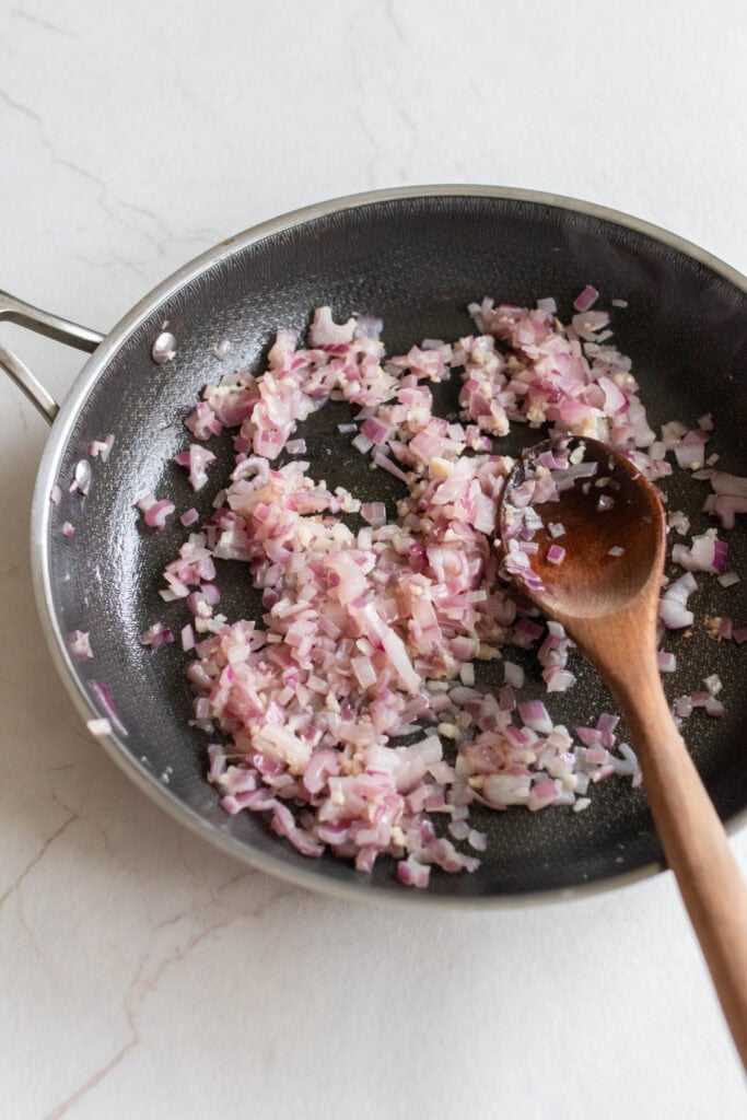 Sautéing garlic and diced onions in a skillet.