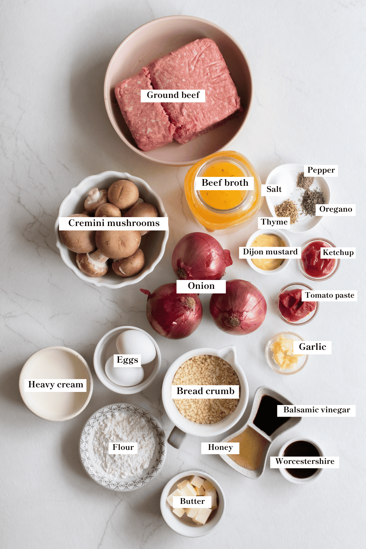 Ground beef, onions, mushroom, broth, spices, and other ingredients for Salisbury steak on a counter top.