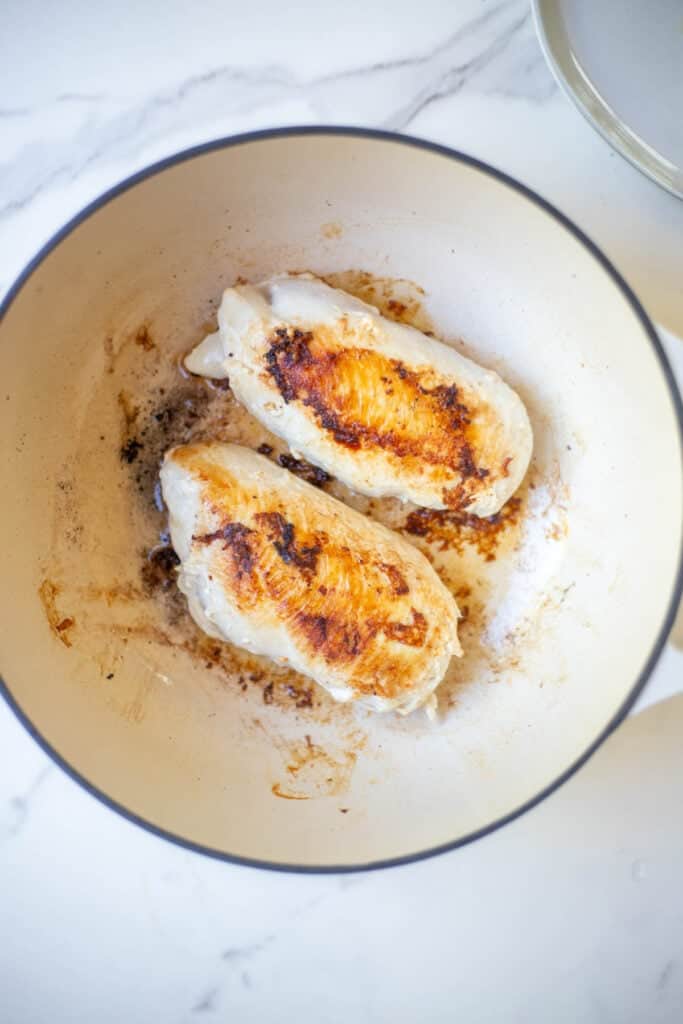 Seared chicken breasts in a Dutch oven.