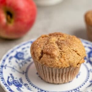 one apple and cinnamon muffin sitting on a blue decorative dessert plate.