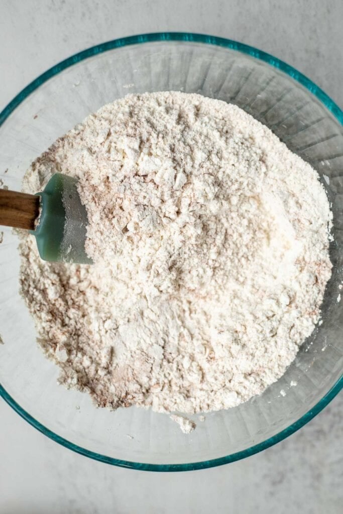 Flour, sugar, baking powder, salt, and cinnamon mixed together in a glass bowl.