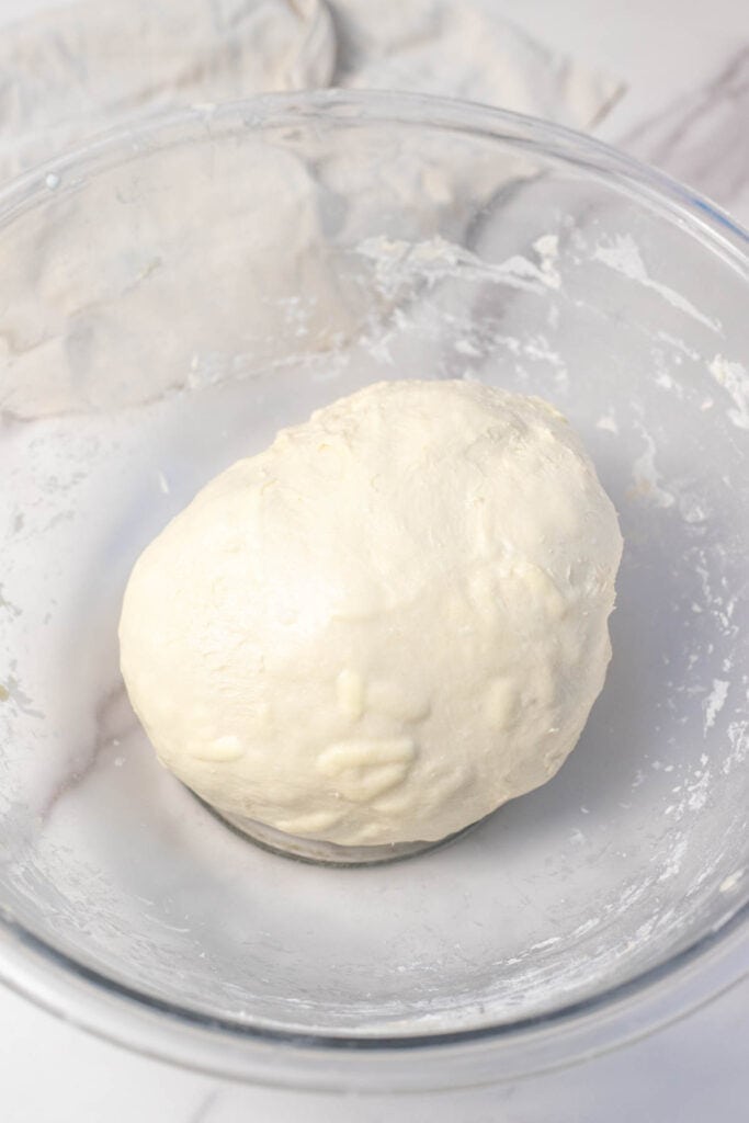 A ball of sourdough croissant dough fermenting in a glass bowl.
