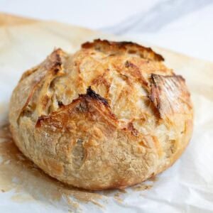 a freshly baked boule of sourdough bread on a cutting board.