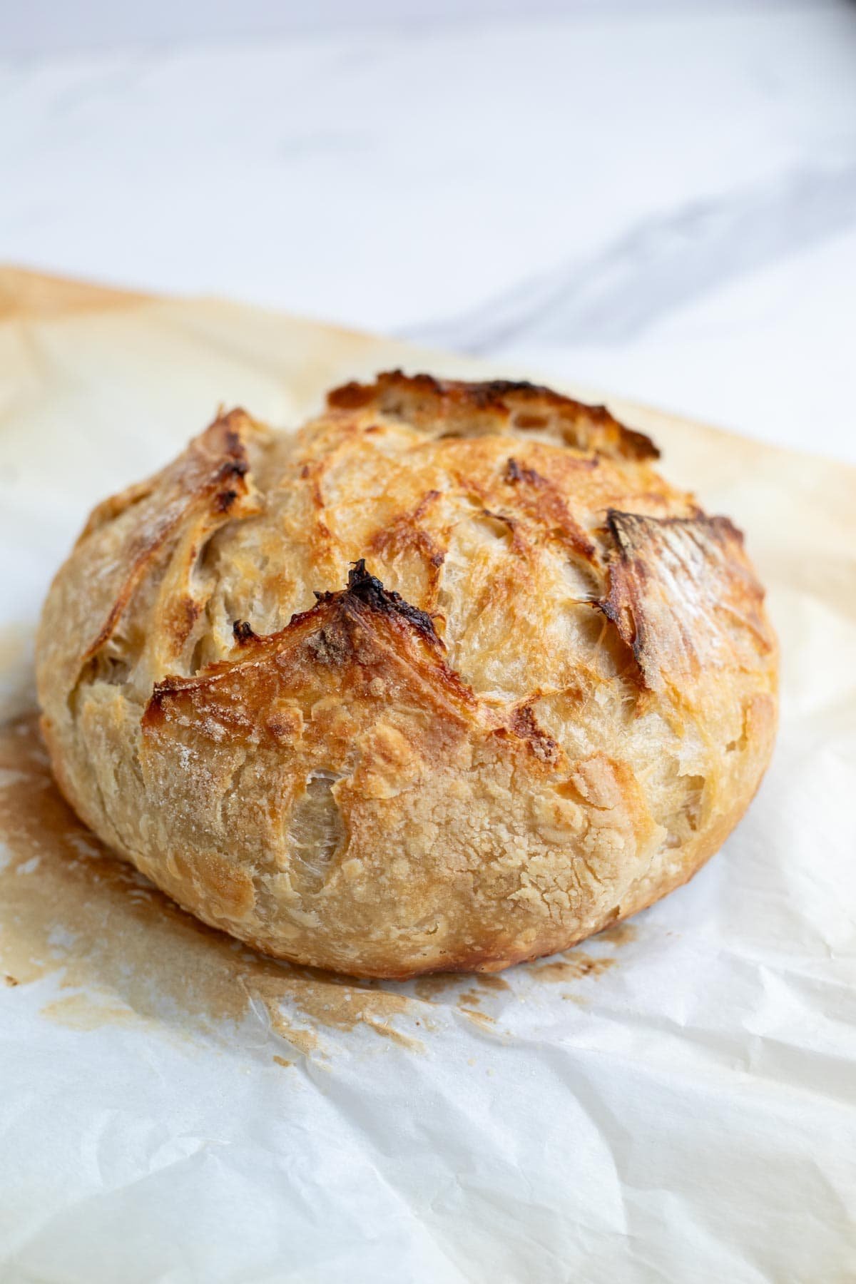 A freshly baked boule of sourdough croissant bread on a cutting board.