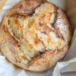 a crusty loaf of sourdough croissant bread on a piece of parchment paper.