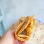 a woman's hand folding two tortillas in half.