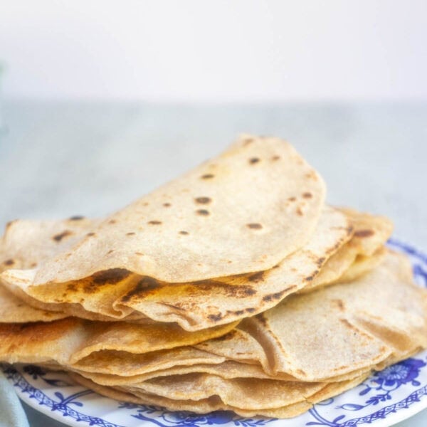 tortillas stacked on top of each other on a blue plate on the counter.
