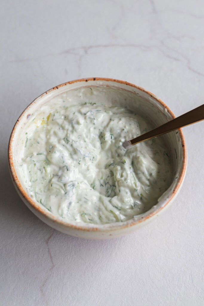 Tzatziki sauce in a bowl with a spoon.