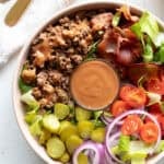 A bowl with ingredients for a cheeseburger.