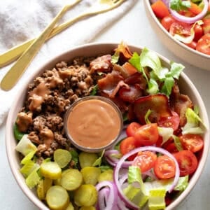 Bowl with burger ingredients and sauce.