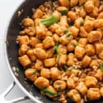 A skillet full of pumpkin gnocchi tossed in a sage butter sauce and topped with fresh sage.