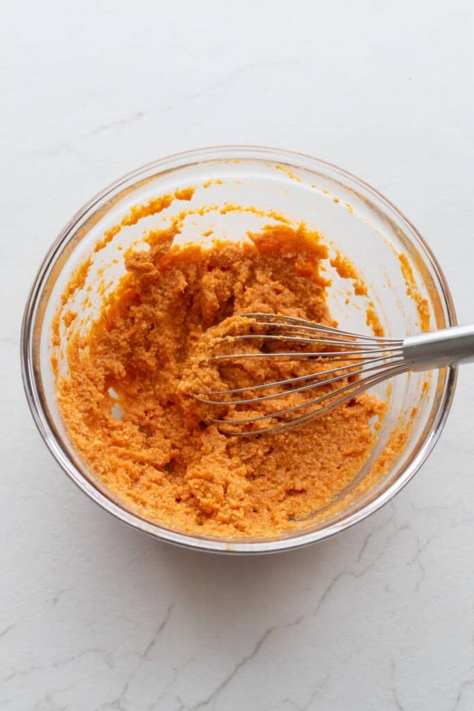 Eggs, parmesan, pumpkin, and ricotta whisked together in a bowl.