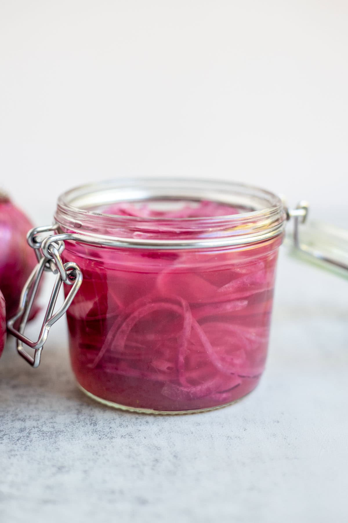 A glass jar of fermented red onions on the counter.
