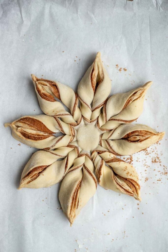 A large rolled out cinnamon roll dough twisted together to look like a star.