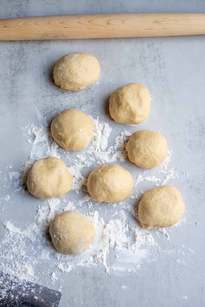 8 smaller balls of sourdough on a floured counter.