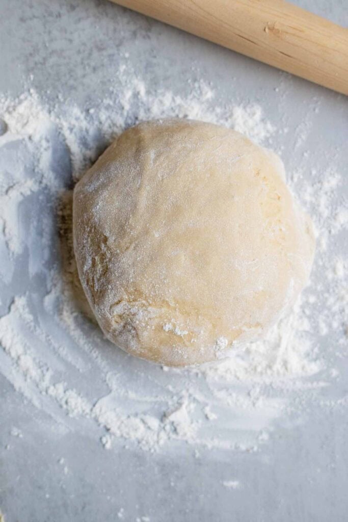 A large ball of dough on a floured counter top.