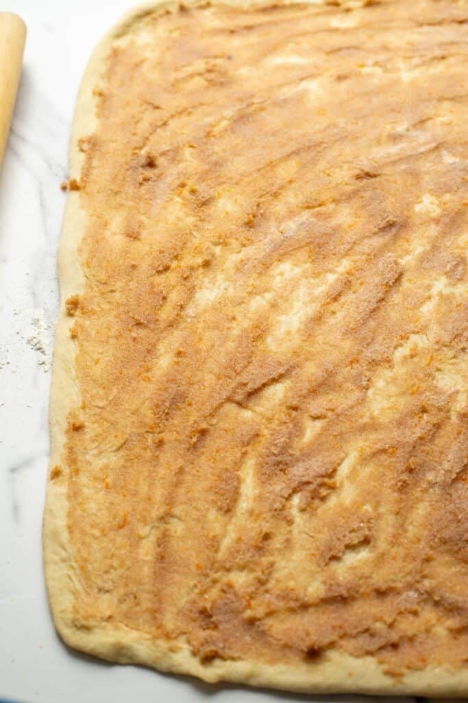 The orange, butter, and cinnamon sugar mixture spread evenly across the dough.