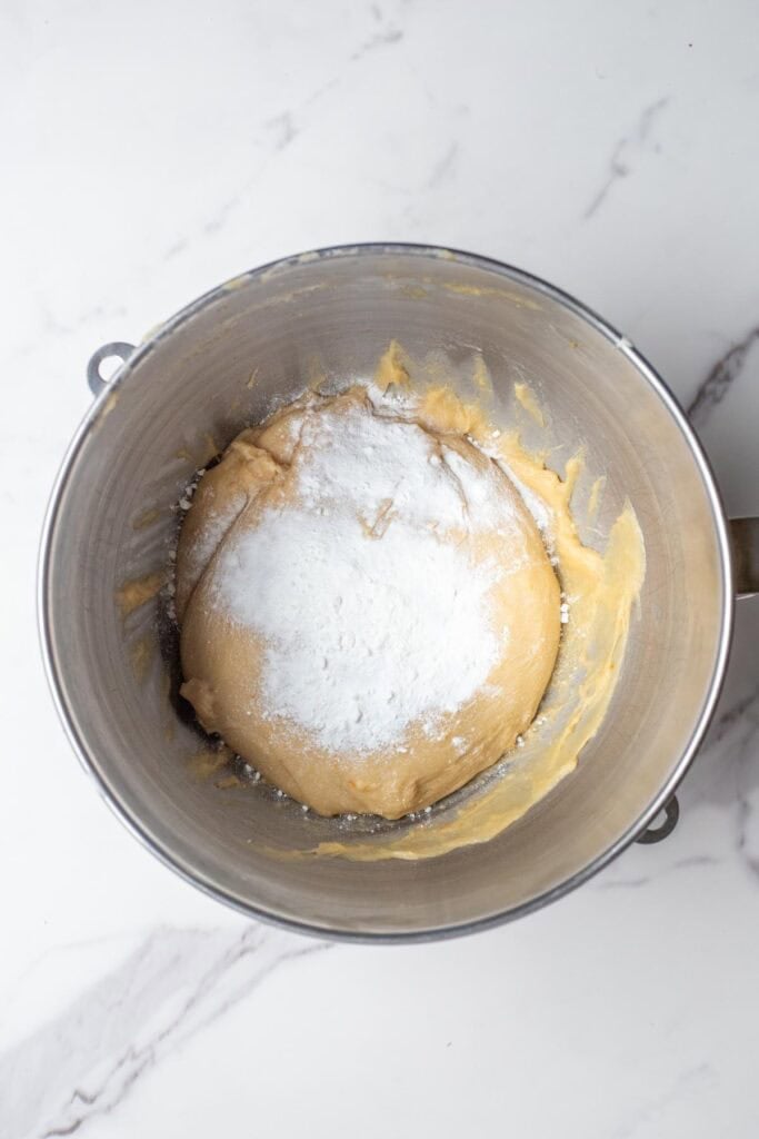 Baking powder, baking soda, and salt on top of the kneaded dough in a mixing bowl.