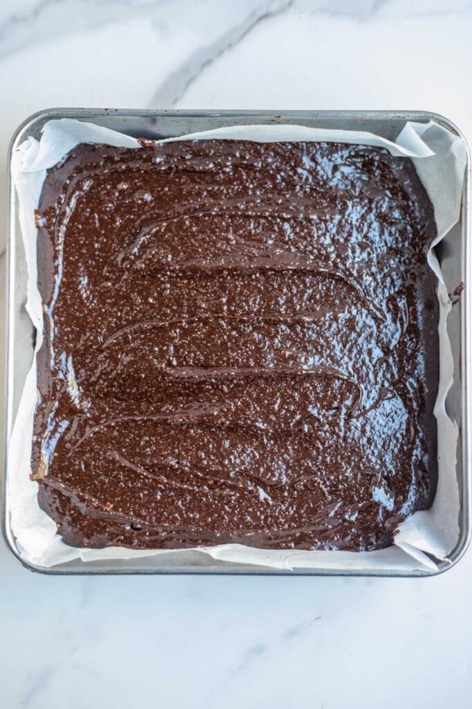 Whole wheat brownie batter poured into a parchment lined baking dish.